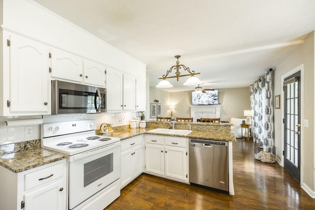 kitchen featuring appliances with stainless steel finishes, a peninsula, a fireplace, white cabinetry, and a sink