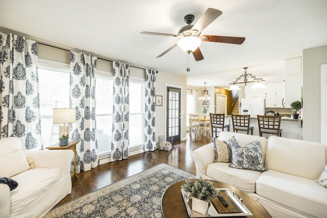 living area featuring ceiling fan with notable chandelier, stairway, and wood finished floors