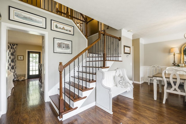 stairs with ornamental molding, a textured ceiling, and wood finished floors