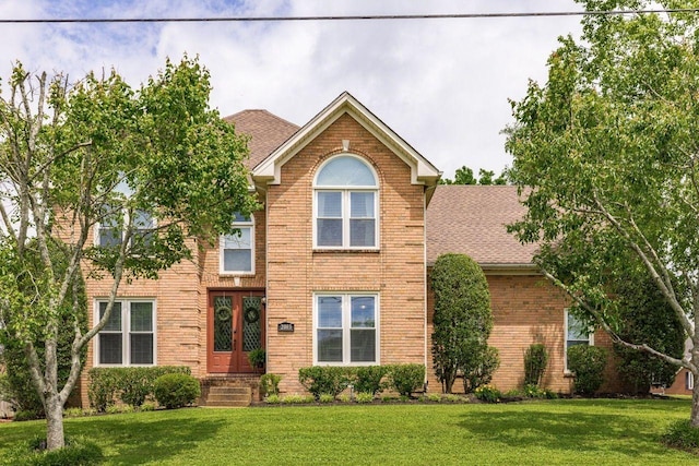 view of front of property featuring french doors, brick siding, and a front yard