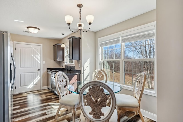 dining space featuring dark wood-style flooring, visible vents, baseboards, and an inviting chandelier