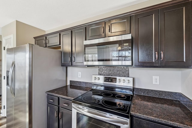 kitchen featuring stainless steel appliances, dark brown cabinets, and dark stone countertops