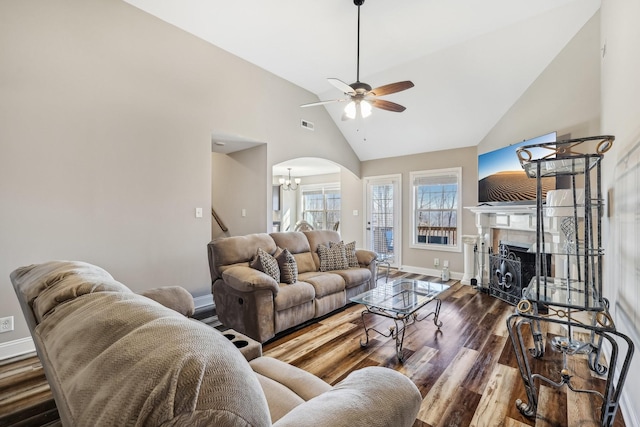 living room with high vaulted ceiling, ceiling fan with notable chandelier, a fireplace, wood finished floors, and baseboards