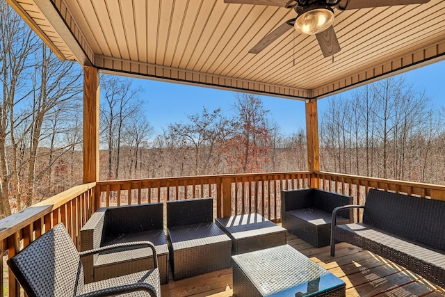 wooden terrace with ceiling fan, outdoor lounge area, and a wooded view