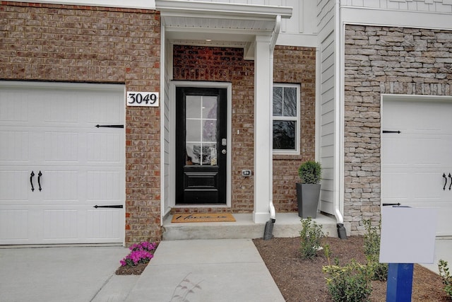 doorway to property with a garage and brick siding