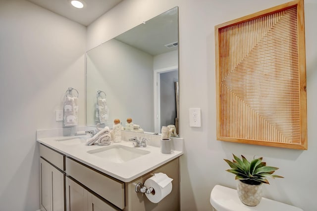 bathroom featuring double vanity, visible vents, toilet, and a sink