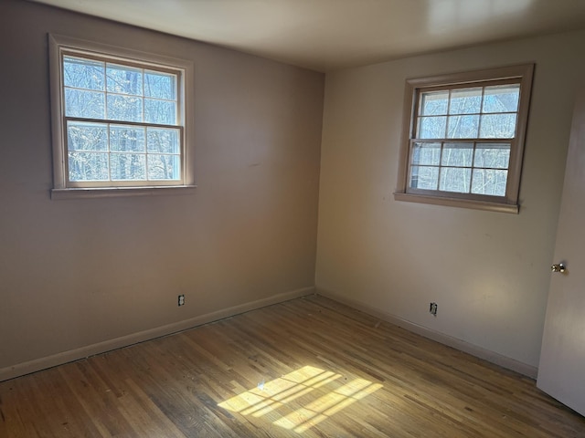 empty room featuring baseboards, wood finished floors, and a healthy amount of sunlight