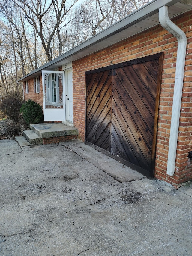 property entrance featuring a garage and brick siding