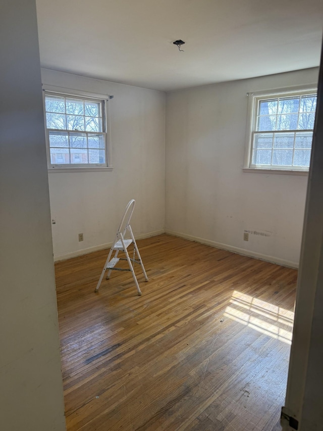 empty room with plenty of natural light, baseboards, and hardwood / wood-style flooring