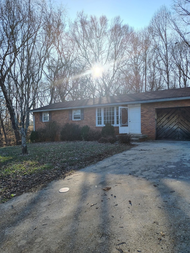 single story home with aphalt driveway, entry steps, brick siding, and an attached garage