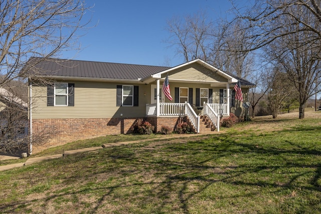 view of front of house featuring metal roof, a porch, a front yard, and brick siding