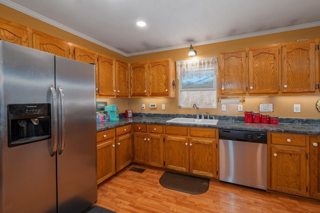 kitchen with a sink, ornamental molding, appliances with stainless steel finishes, light wood-type flooring, and brown cabinetry