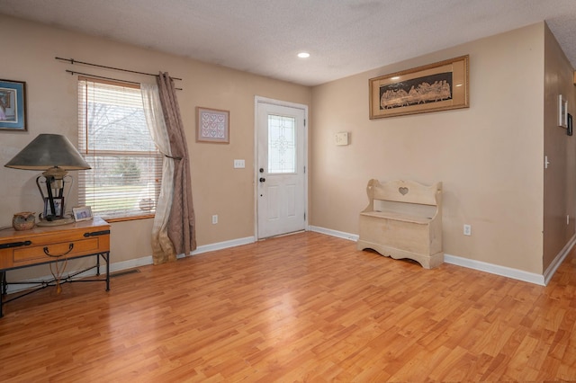 entrance foyer featuring a textured ceiling, light wood finished floors, recessed lighting, and baseboards