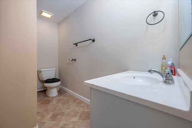 half bathroom featuring toilet, tile patterned floors, baseboards, and vanity