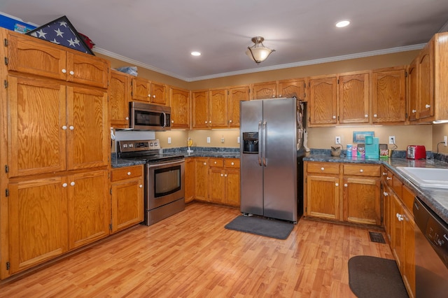 kitchen featuring light wood finished floors, appliances with stainless steel finishes, brown cabinetry, and ornamental molding