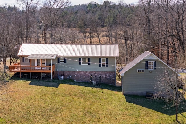 back of house with a wooden deck, metal roof, a wooded view, and a yard