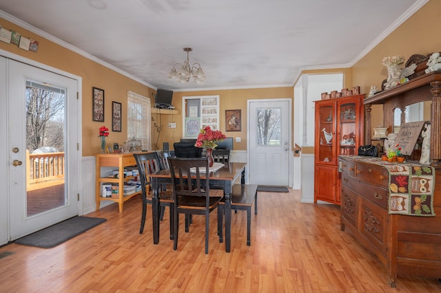 dining room featuring a notable chandelier, crown molding, wainscoting, and light wood-style floors