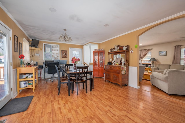 dining room featuring arched walkways, visible vents, ornamental molding, a chandelier, and light wood-type flooring