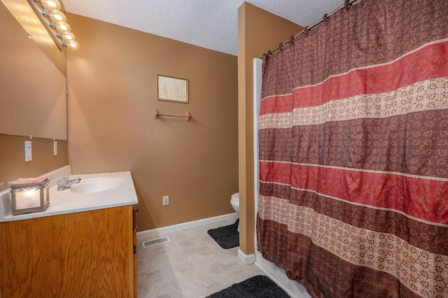 bathroom featuring a textured ceiling, toilet, vanity, visible vents, and baseboards