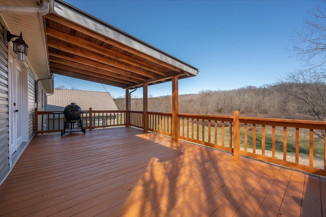 deck with area for grilling and a view of trees