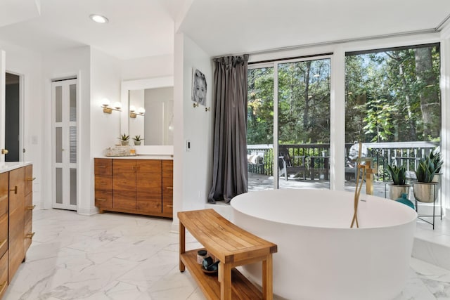 bathroom featuring marble finish floor, recessed lighting, a soaking tub, and vanity