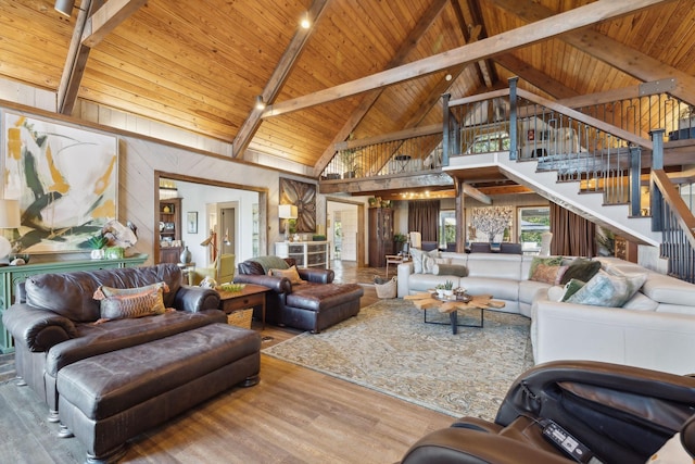 living area featuring beam ceiling, wood finished floors, high vaulted ceiling, wooden ceiling, and stairs