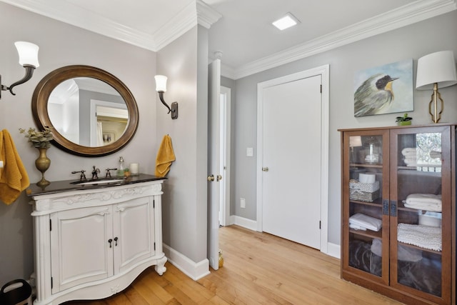 bathroom with crown molding, vanity, baseboards, and wood finished floors