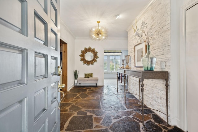 foyer with ornamental molding, stone flooring, baseboards, and an inviting chandelier