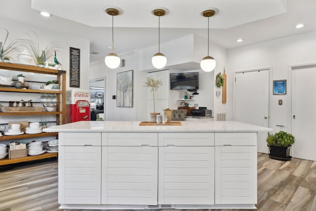 kitchen with light stone counters, recessed lighting, a kitchen island, light wood-style floors, and pendant lighting