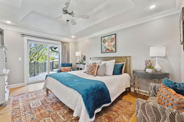 bedroom featuring access to exterior, a tray ceiling, light wood-style floors, and ornamental molding