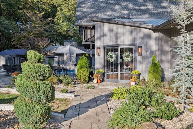 doorway to property featuring a balcony and a shingled roof