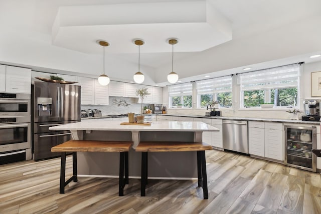 kitchen featuring white cabinets, decorative backsplash, a breakfast bar area, stainless steel appliances, and a sink