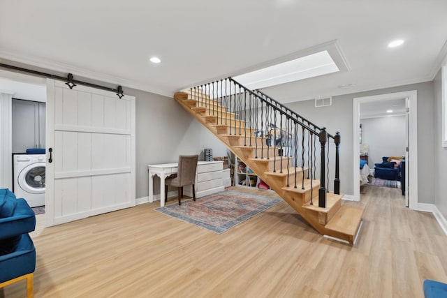 living room with light wood finished floors, a barn door, visible vents, washer / clothes dryer, and stairs