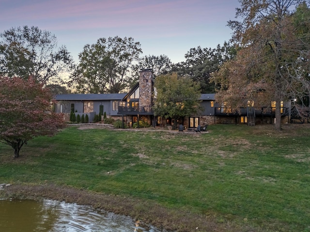 yard at dusk with a deck with water view