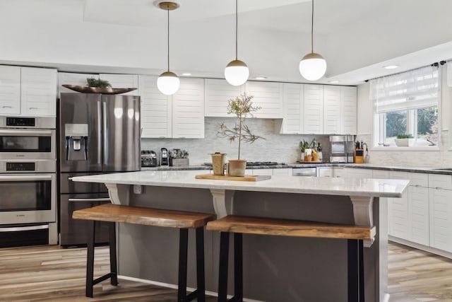 kitchen with appliances with stainless steel finishes, backsplash, and a kitchen bar