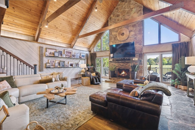 living room with wood walls, a stone fireplace, wooden ceiling, hardwood / wood-style floors, and stairs