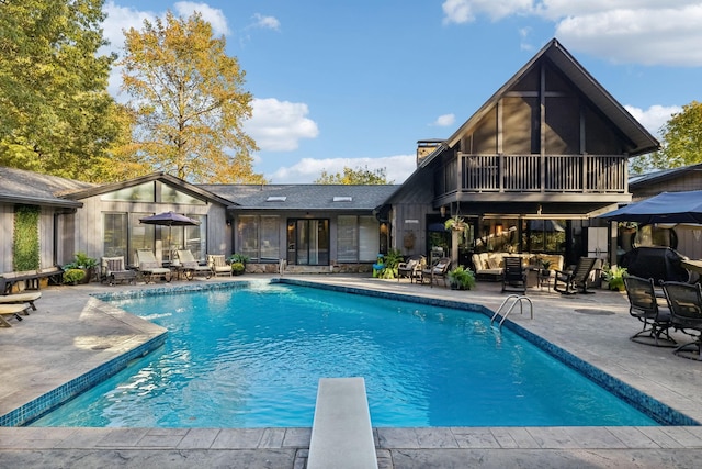 outdoor pool featuring a sunroom, an outdoor hangout area, a diving board, and a patio