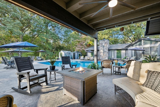 view of patio with an outbuilding, an exterior structure, an outdoor pool, and a fire pit