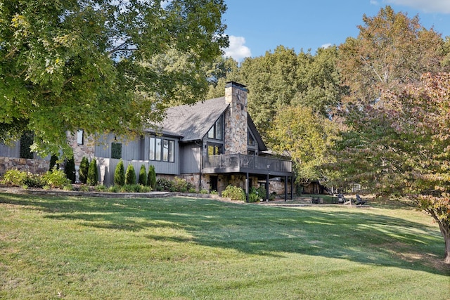 view of side of property featuring stone siding, a chimney, a lawn, and a wooden deck