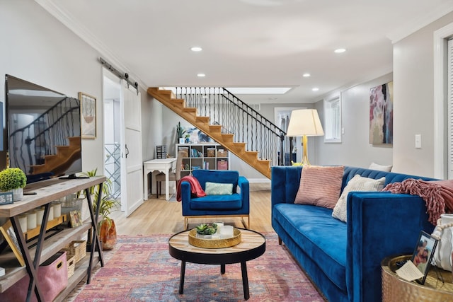 living room featuring recessed lighting, stairway, a barn door, ornamental molding, and light wood-type flooring