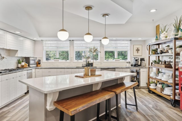 kitchen with a healthy amount of sunlight, light wood finished floors, beverage cooler, and backsplash