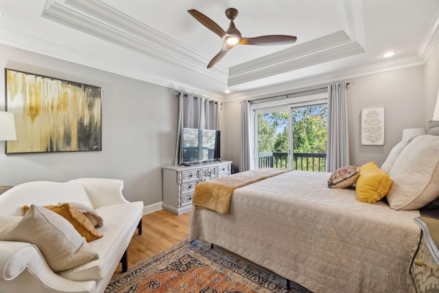 bedroom with a ceiling fan, a raised ceiling, light wood-style flooring, and access to exterior