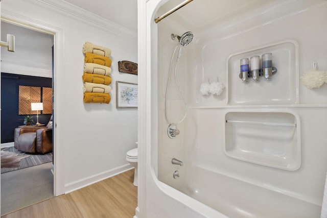 bathroom with crown molding, shower / bathing tub combination, toilet, wood finished floors, and baseboards