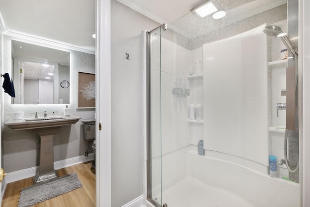 bathroom with crown molding, toilet, a stall shower, wood finished floors, and baseboards