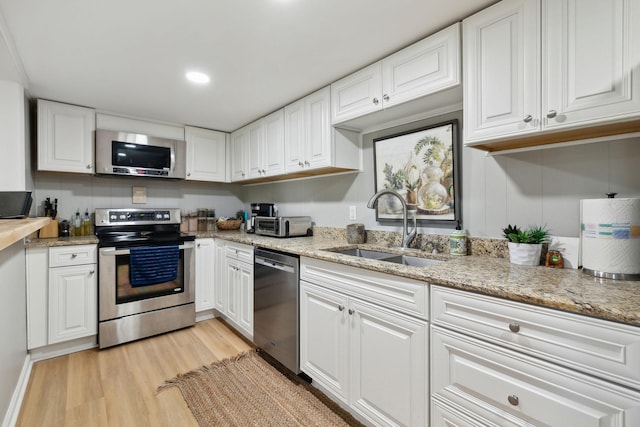 kitchen with stainless steel appliances, a sink, and white cabinetry