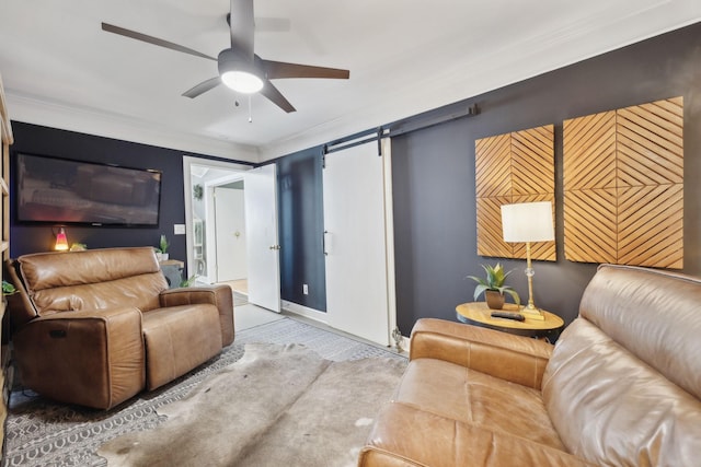 living room featuring ornamental molding, a ceiling fan, and a barn door