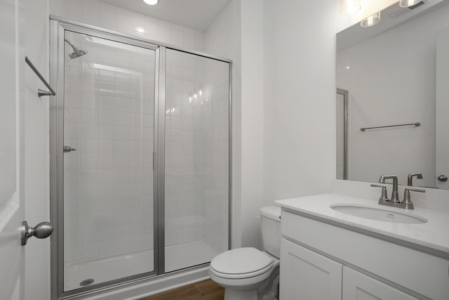 bathroom featuring toilet, vanity, a shower stall, and visible vents