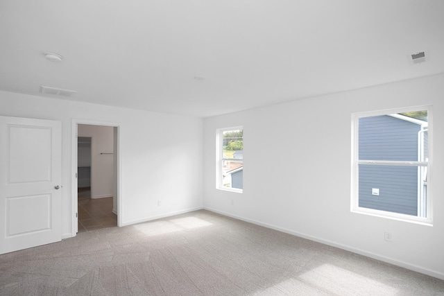 unfurnished room with carpet floors, visible vents, and baseboards