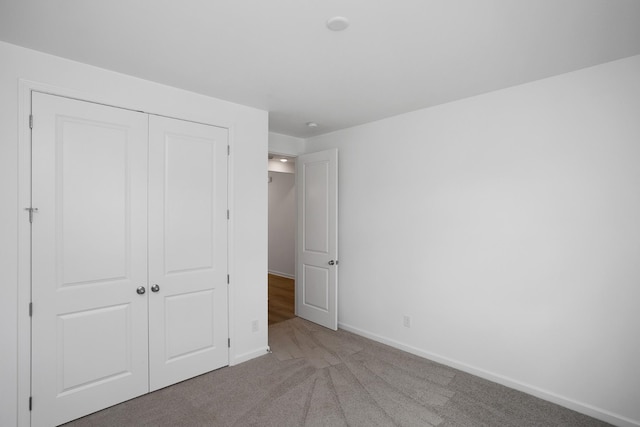 unfurnished bedroom featuring carpet floors, baseboards, and a closet