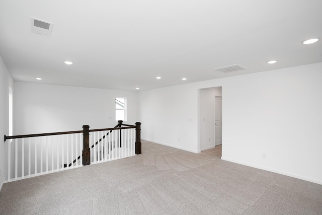 spare room with baseboards, light colored carpet, visible vents, and recessed lighting